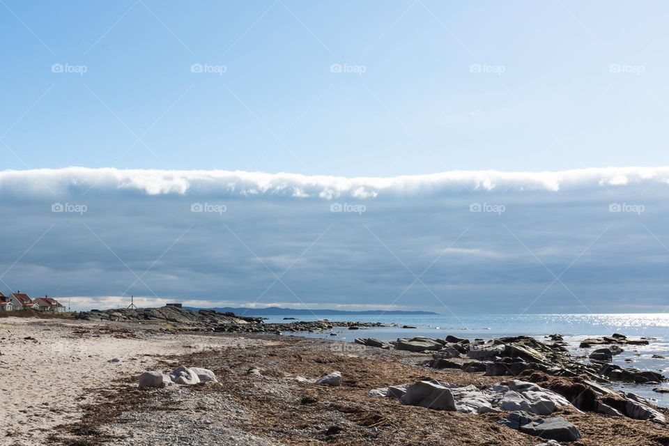Evident border between the clouds and the blue sky over the ocean and coastal line 
