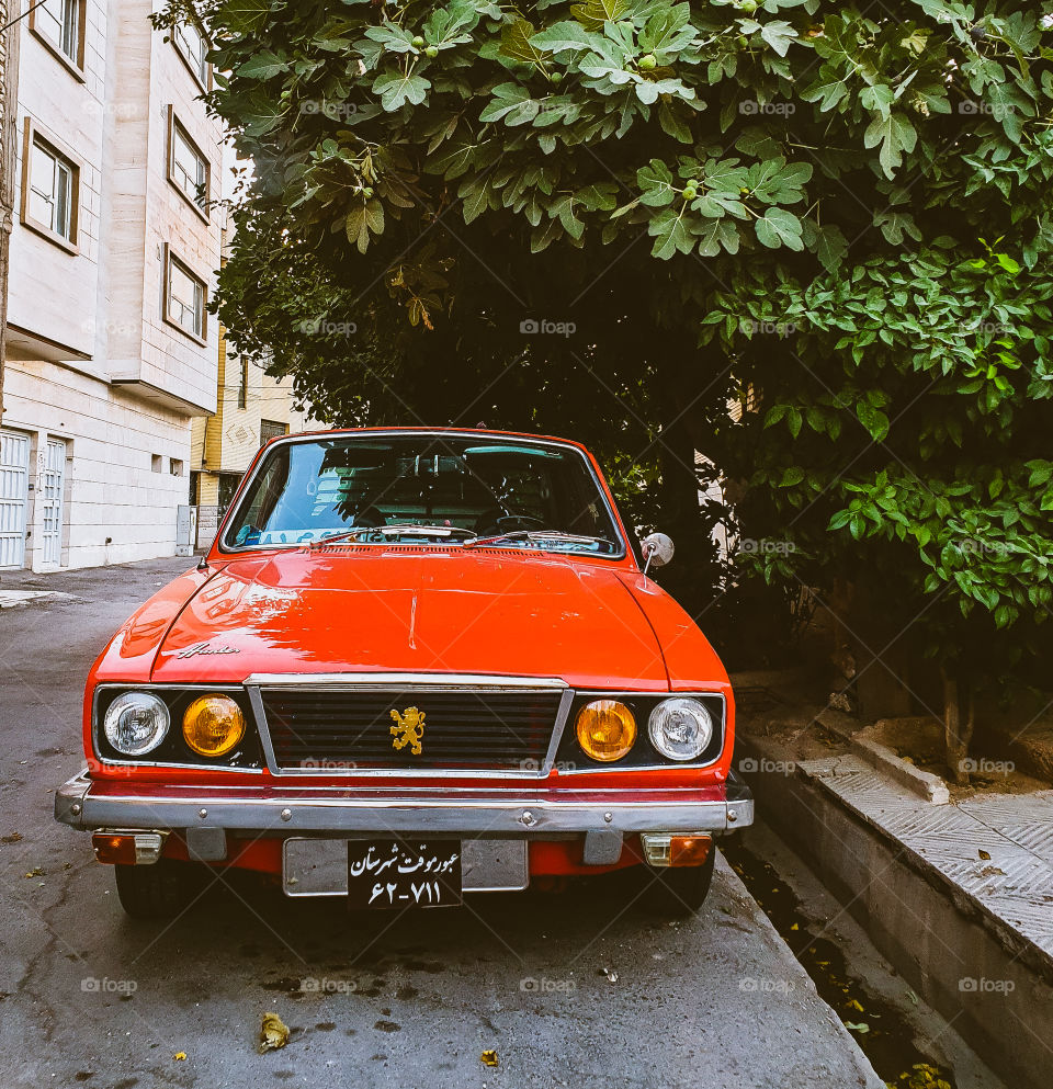 Red old car parked in the street.