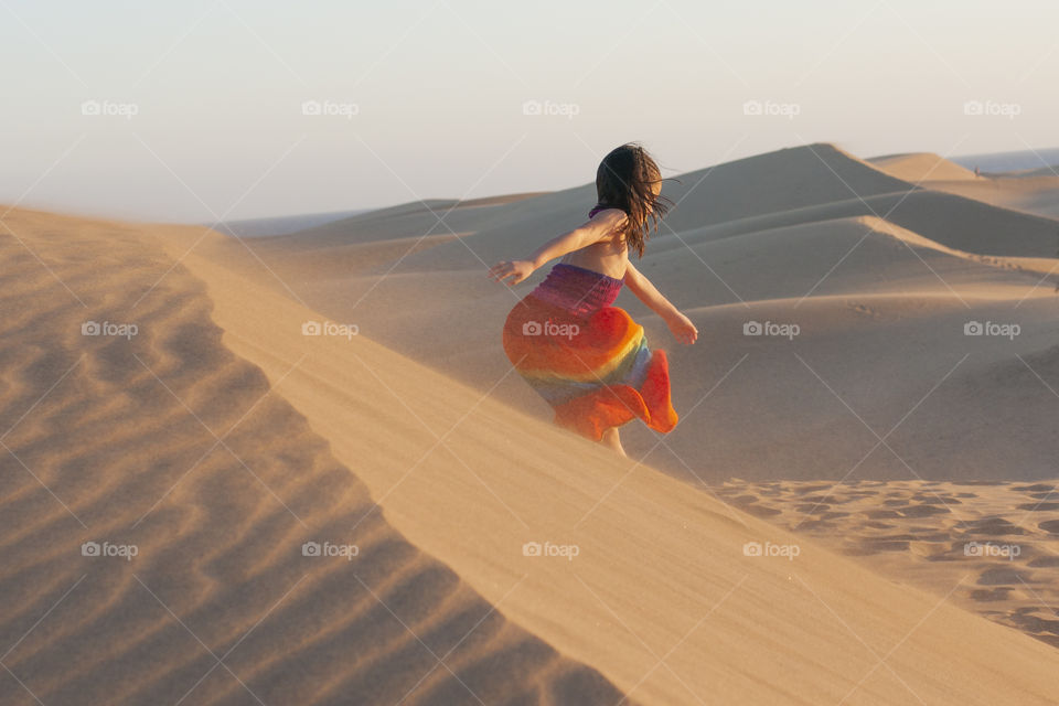 Little girl runs on a sand dune. Maspalomas, Gran Canaria, Canary Islands, Spain 