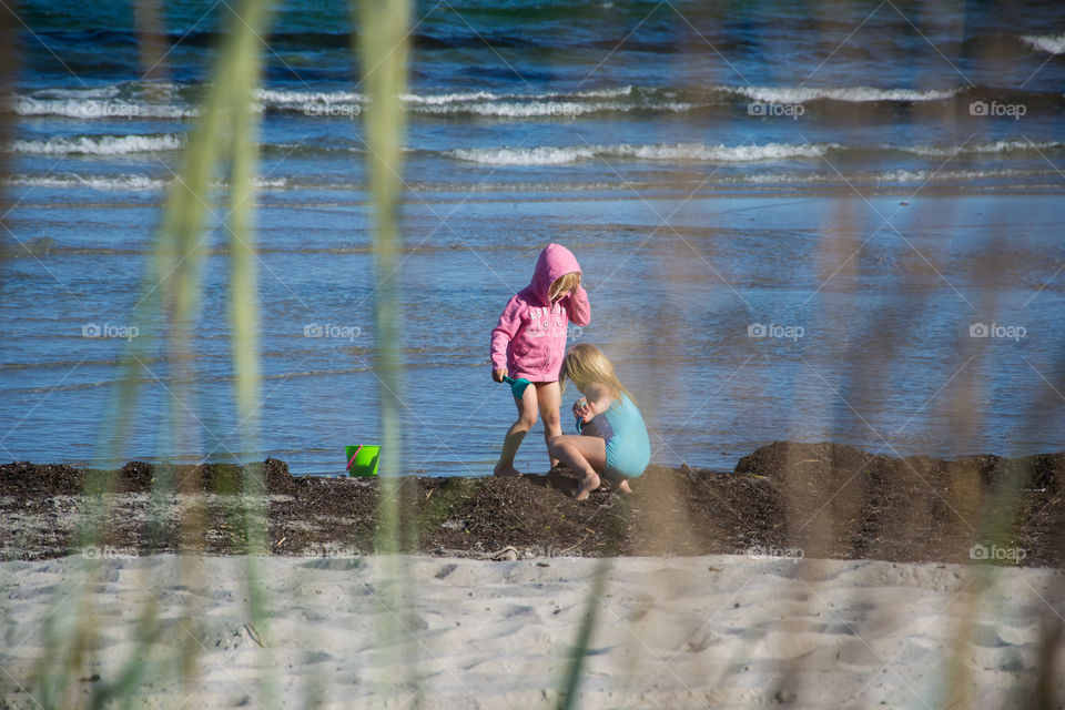 Two young sisters age five and three playing on the beach in Höllviken in Sweden.