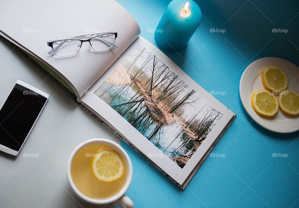 Top view on work desk with photobook and tea cup