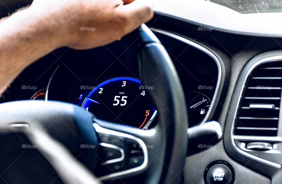 Close-up photo of hand hodling steering wheel of a modern car while driving