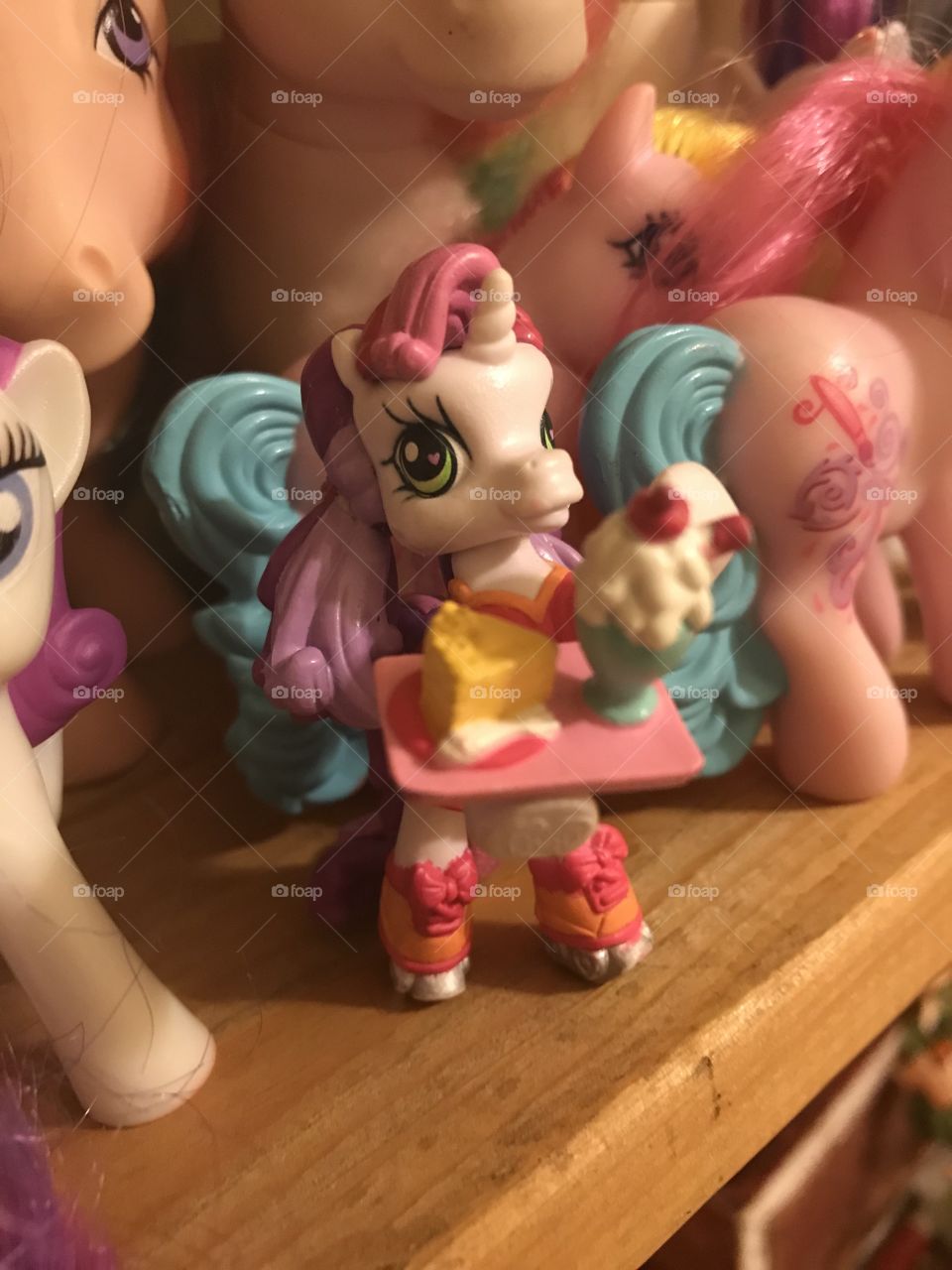 A My Little Pony toy of a skateboarding pony carrying food, surrounded by other pony toys