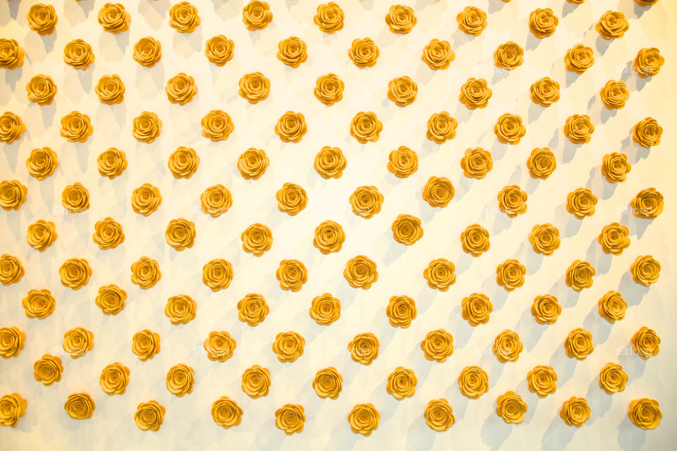 Symmetry: wall of yellow fabric flowers in a repeating pattern