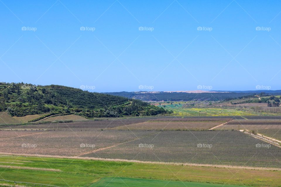 View from the top of the castle of Obidos in Portugal.  View over the hills and agricultural lands. Blue sky and mountains on the horizon.
