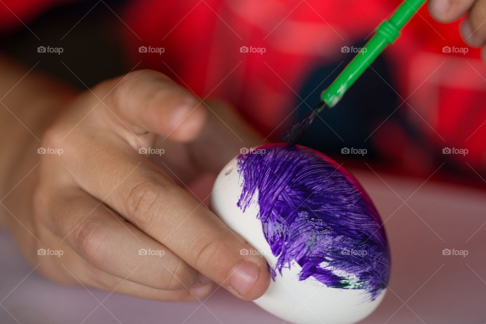 kid painting eggshell with tempera and brush