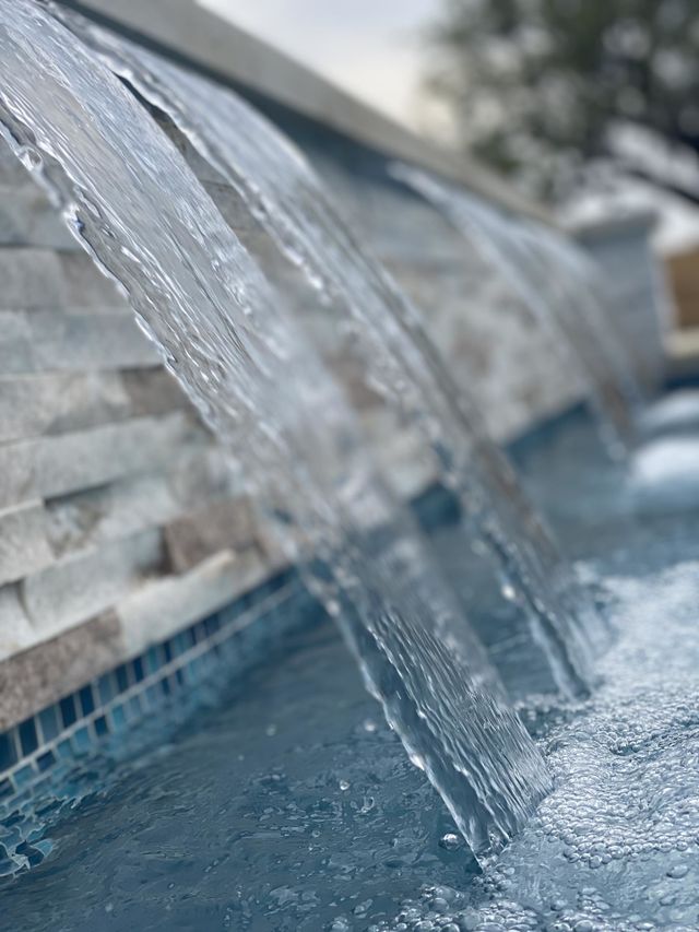 Pool waterfall closeup water flowing into large pool