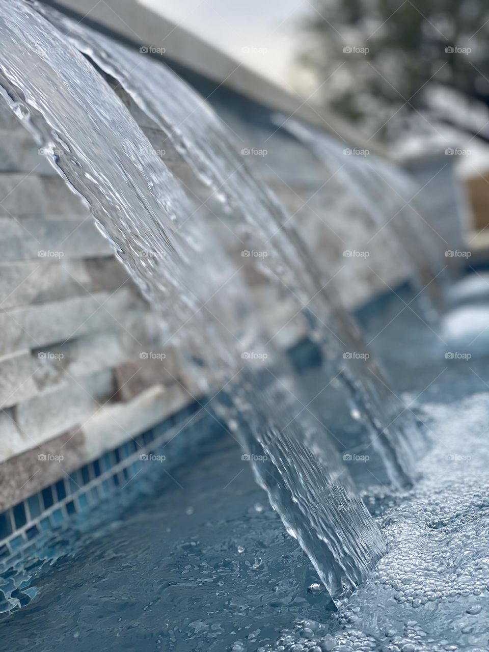 Pool waterfall closeup water flowing into large pool