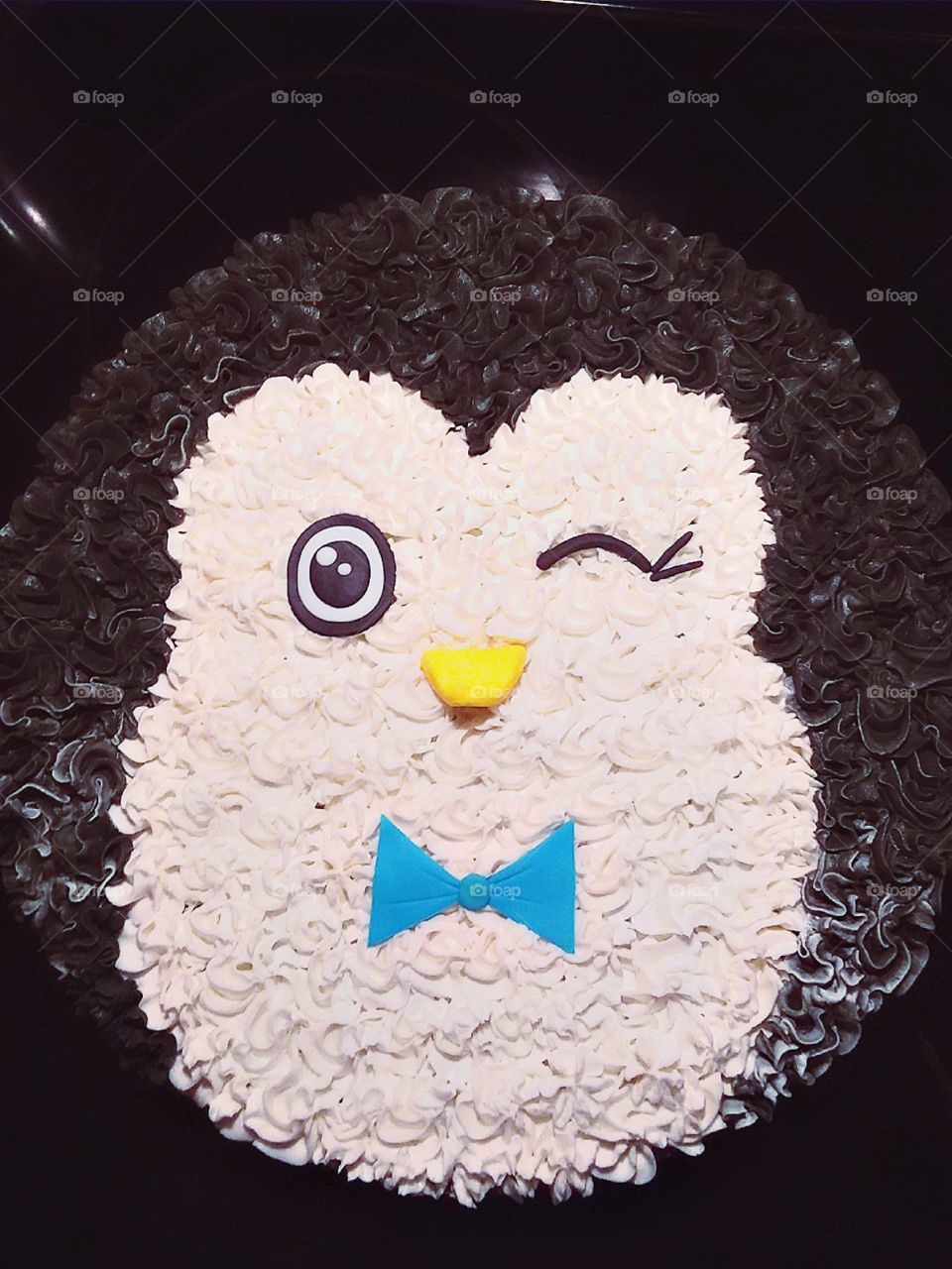 Stunning winter cookie cake decorated like a penguin winking and wearing a bowtie
