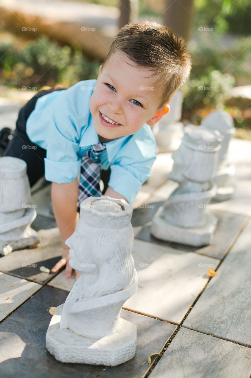 5 year old boy playing chess outside 