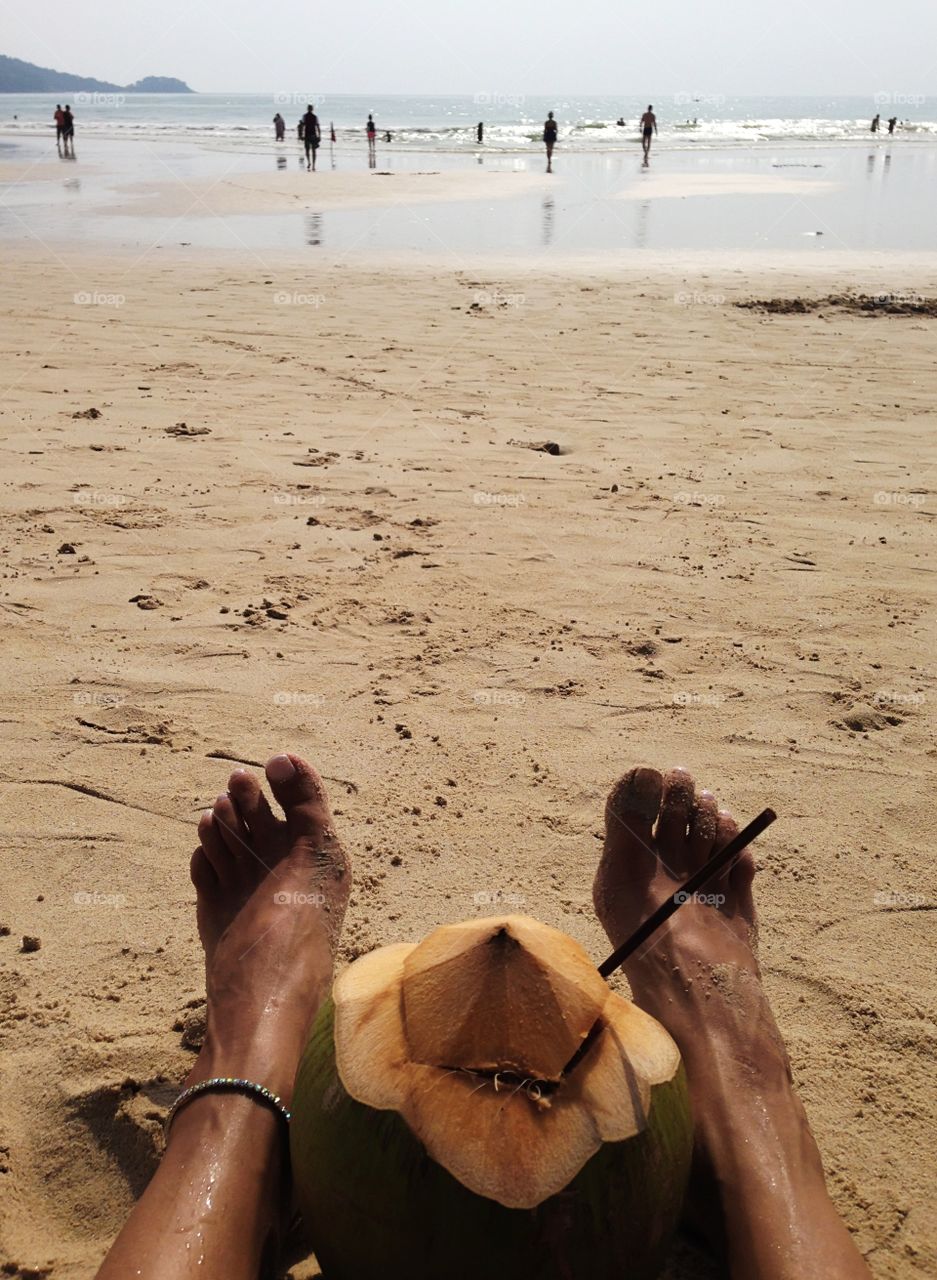 Enjoying reflux with coconut cocktail on sandy beach 