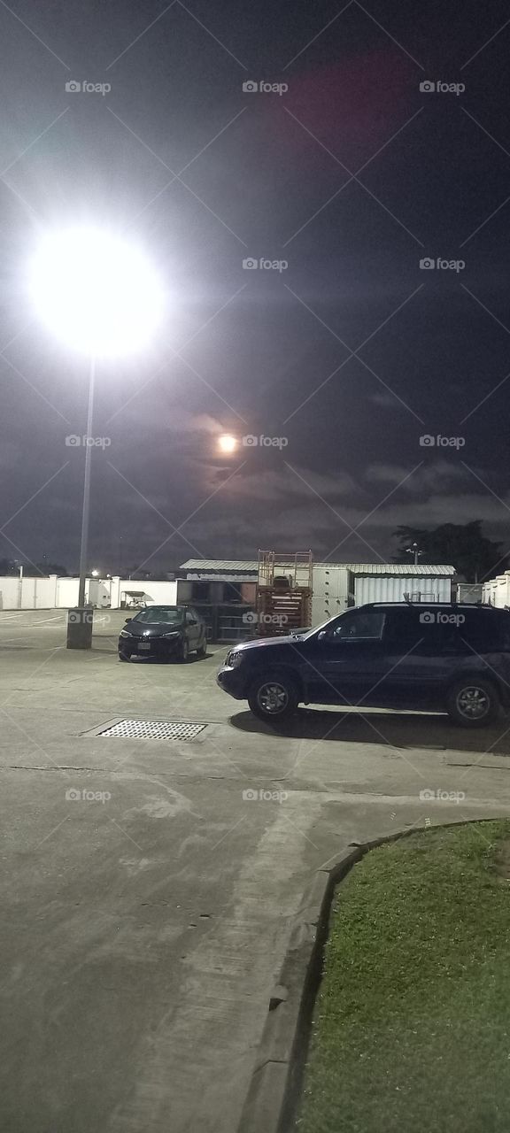 Full moon in night sky over a parking lot