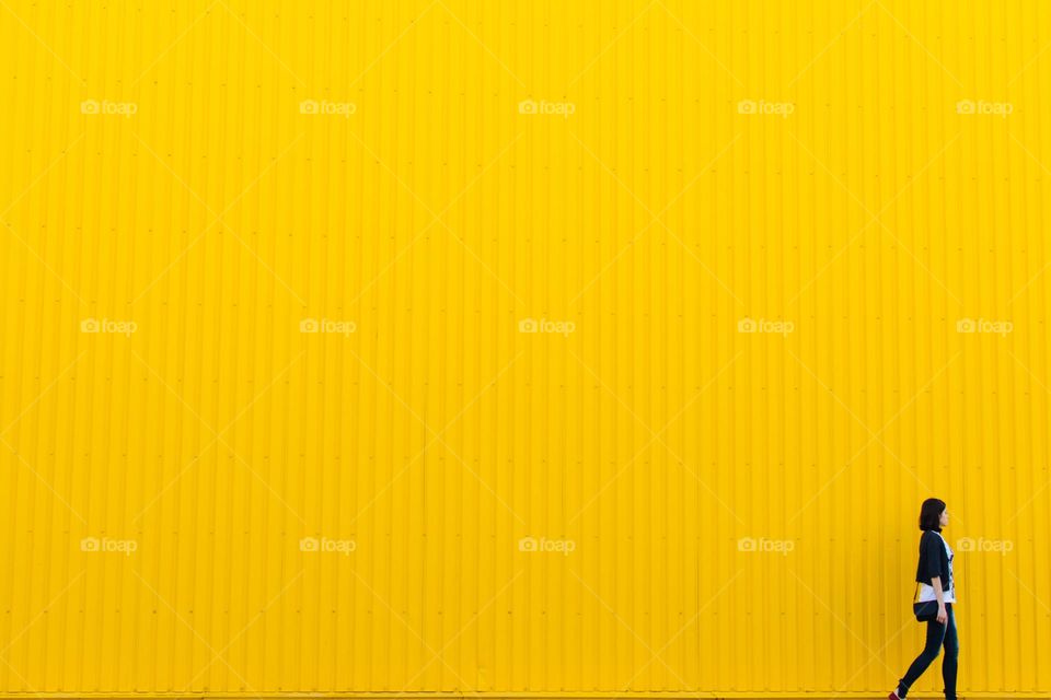 A beautiful lady was passing through a beautiful yellow wall.