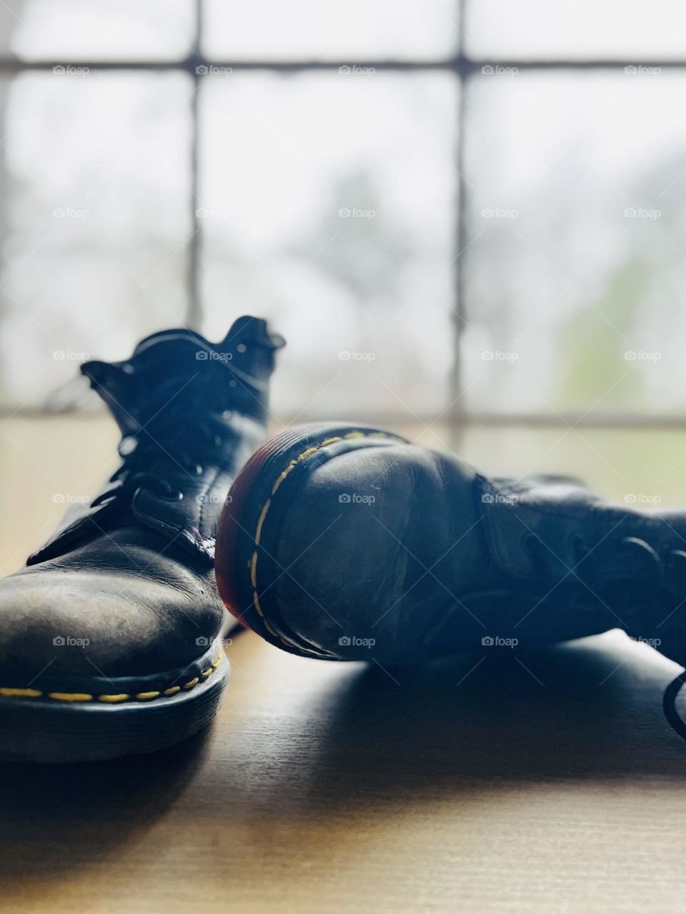 Closeup pair of worn classic Doc Marten boots backlit by window