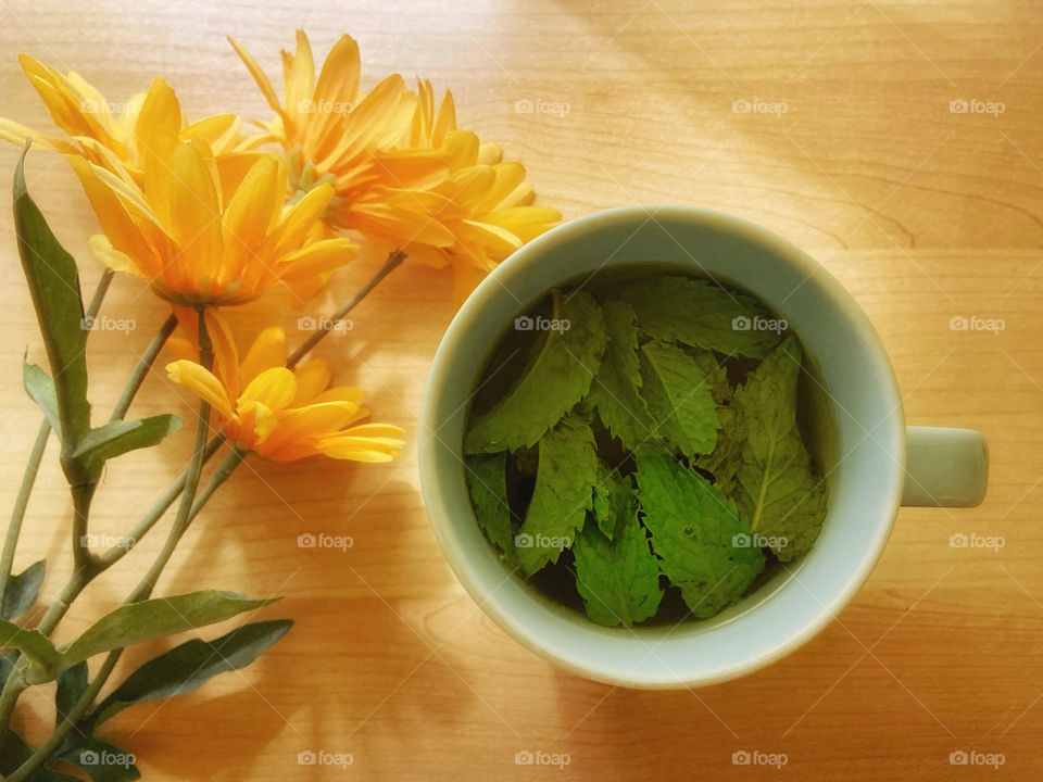 A cup of green tea with lemon and fresh mint leaves