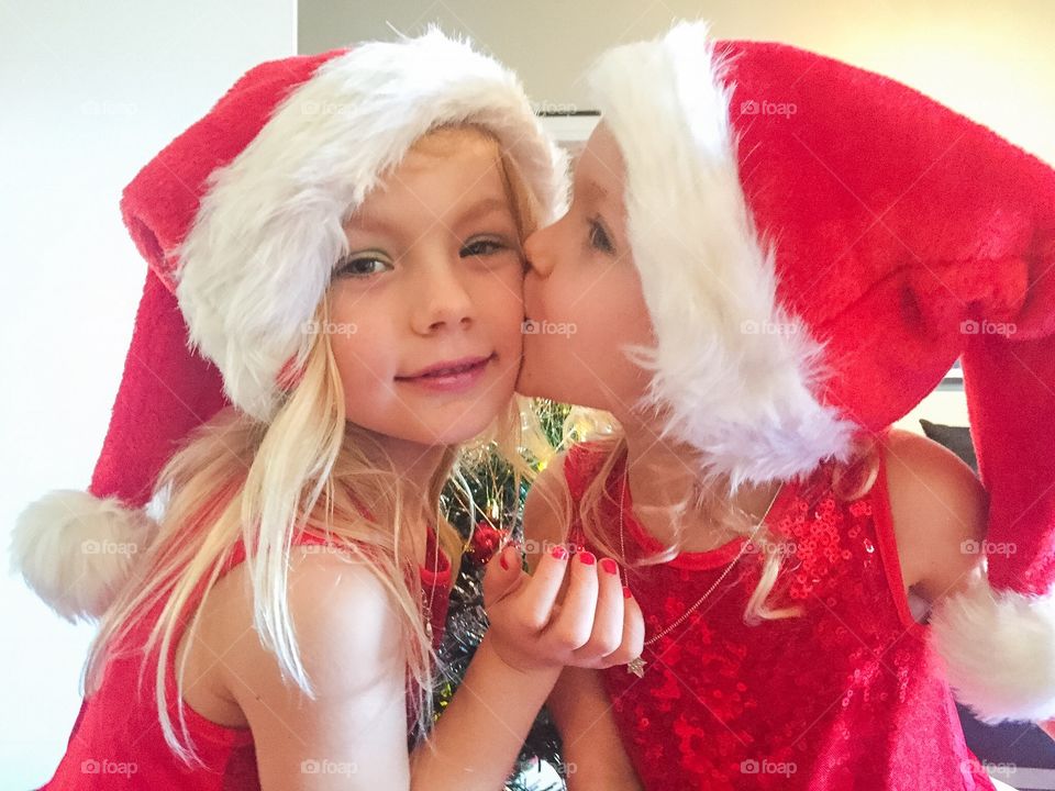 Two young sisters kissing on Christmas eve in Sweden. 