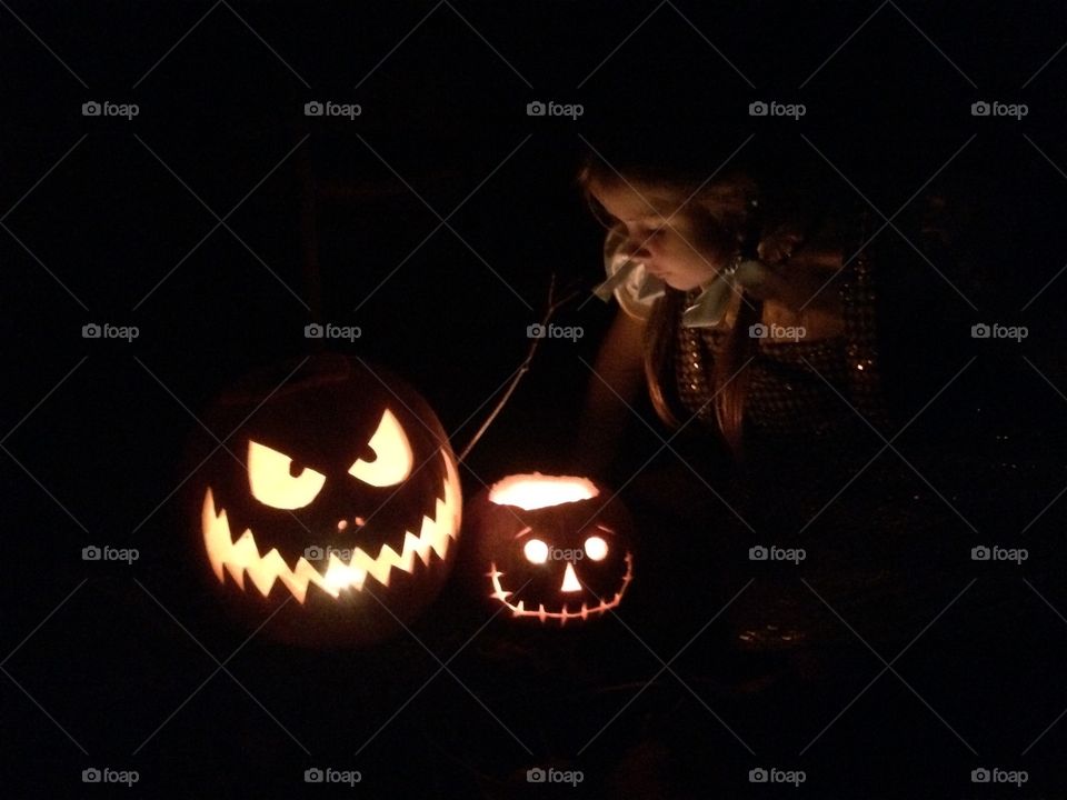 Beautiful photo of young girl during Halloween looking into carved pumpkins!! 