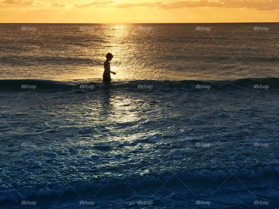 Small boy enjoying an ocean sunset.