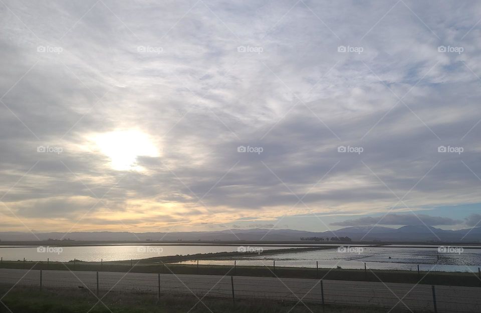 Sun setting over California rice fields, with amazing clouds
