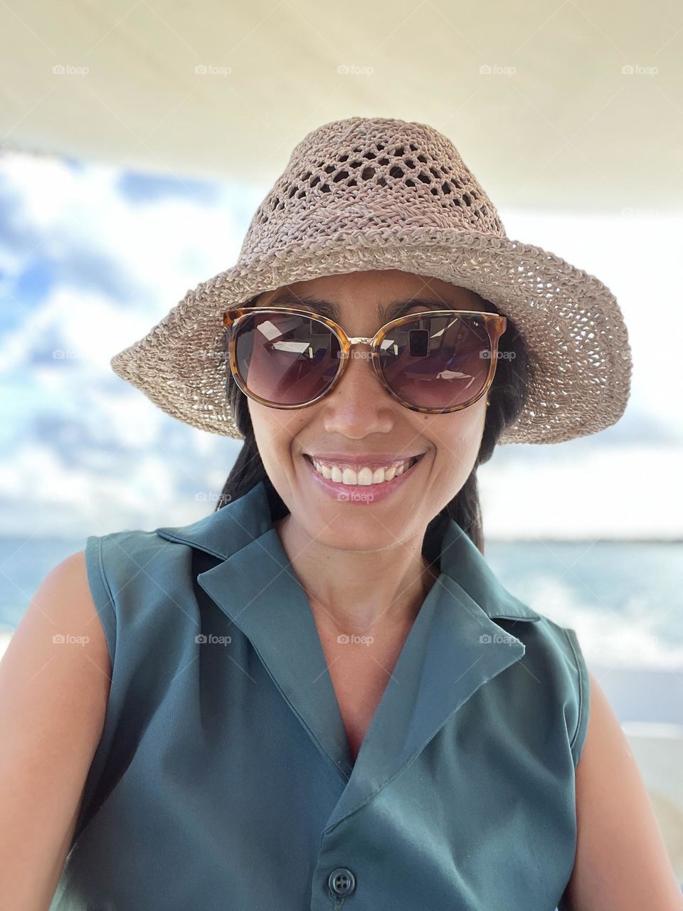 Portrait of young adult woman wearing a hat and sunglasses with smile on her face. 