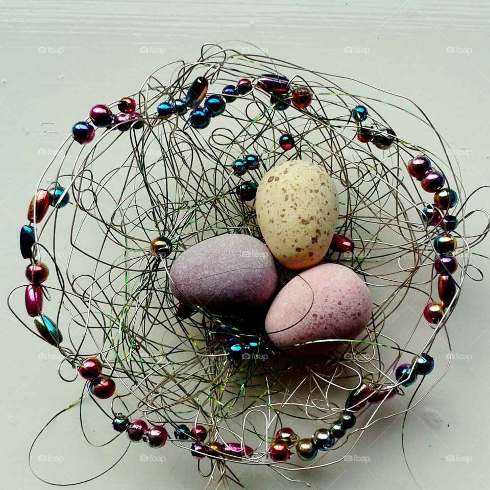 Some tiny coloured Easter eggs in a nest made of fine wire and beads.