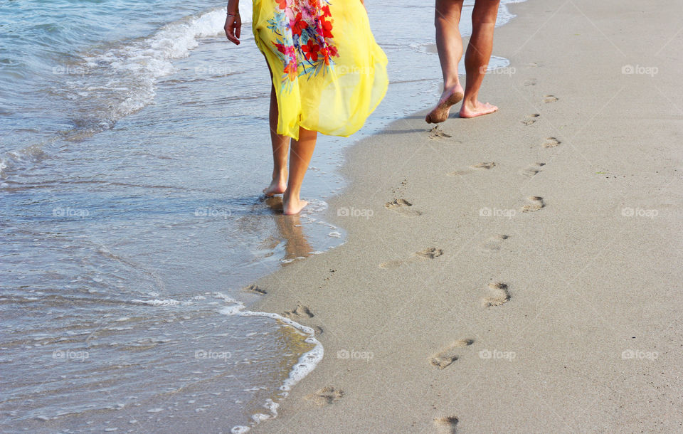 A man and a woman walking on the beach, seashore