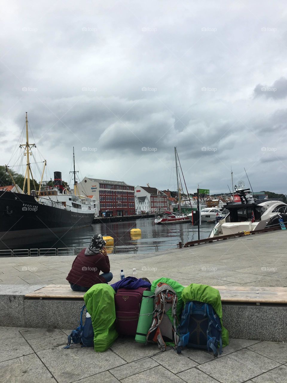 Traveller is sitting on the bench with his backpacks