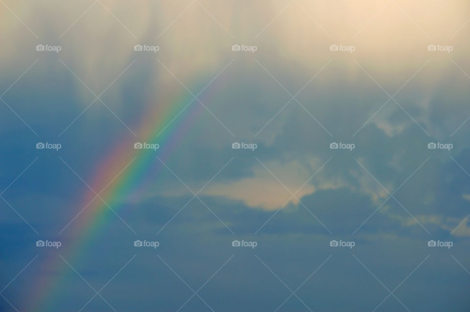 Rainbow in a cloud filled sky landscape in the clouds meteorological phenomenon caused by reflection, refraction and dispersion of water in light 
