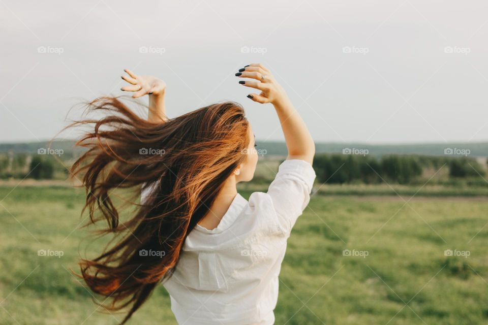 Beautiful long hair girl in white clothes in field, view from back. Sensitivity to nature concept