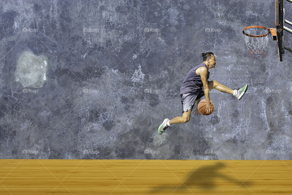 Basketball in hand man jumping Throw a basketball hoop On the wooden floor Background plaster wall loft  with The pattern of cracks.