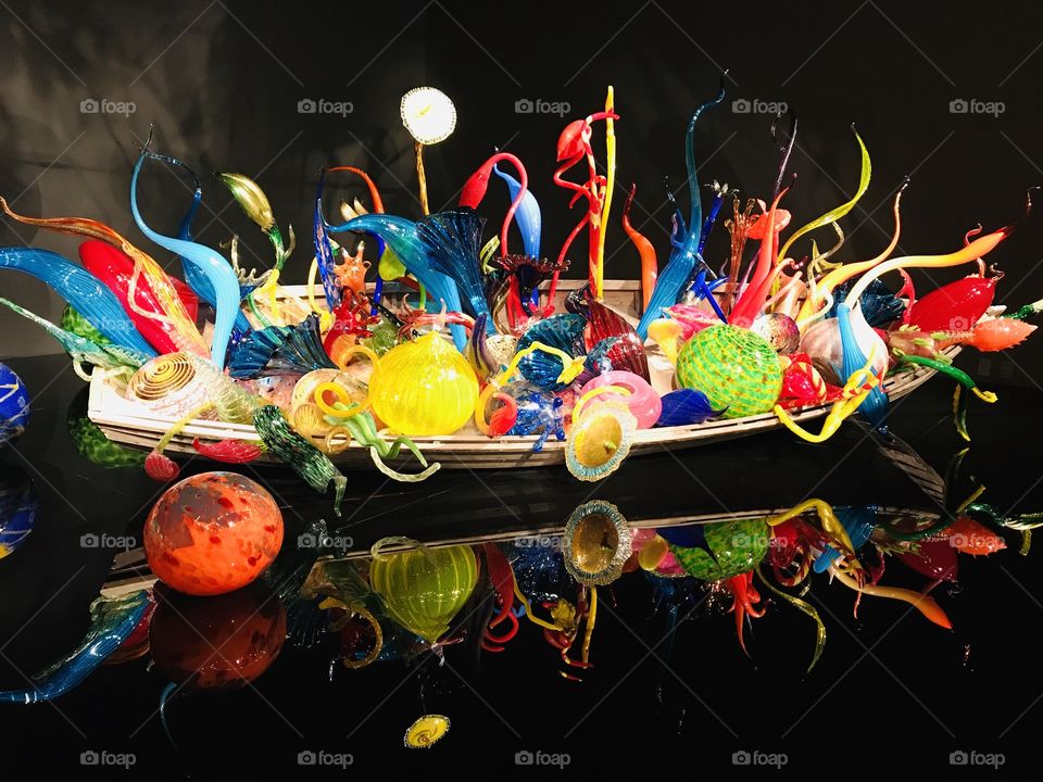 Gorgeous rainbow colored glass balls and ribbons in boat displayed against reflecting black background! 