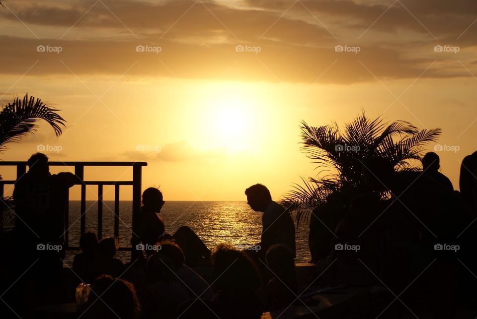 a couple sitting while the sun is setting