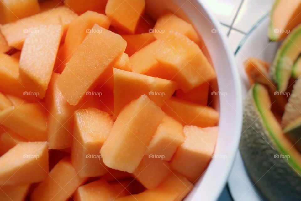 Cantaloupe chunks in a bowl with the peel next to it