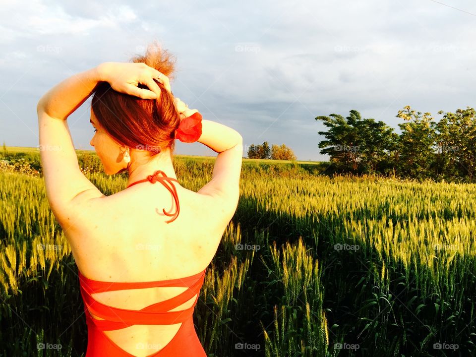 Woman in backless dress standing in front of farm field