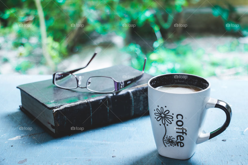 Coffee, book and glasses on garden's table