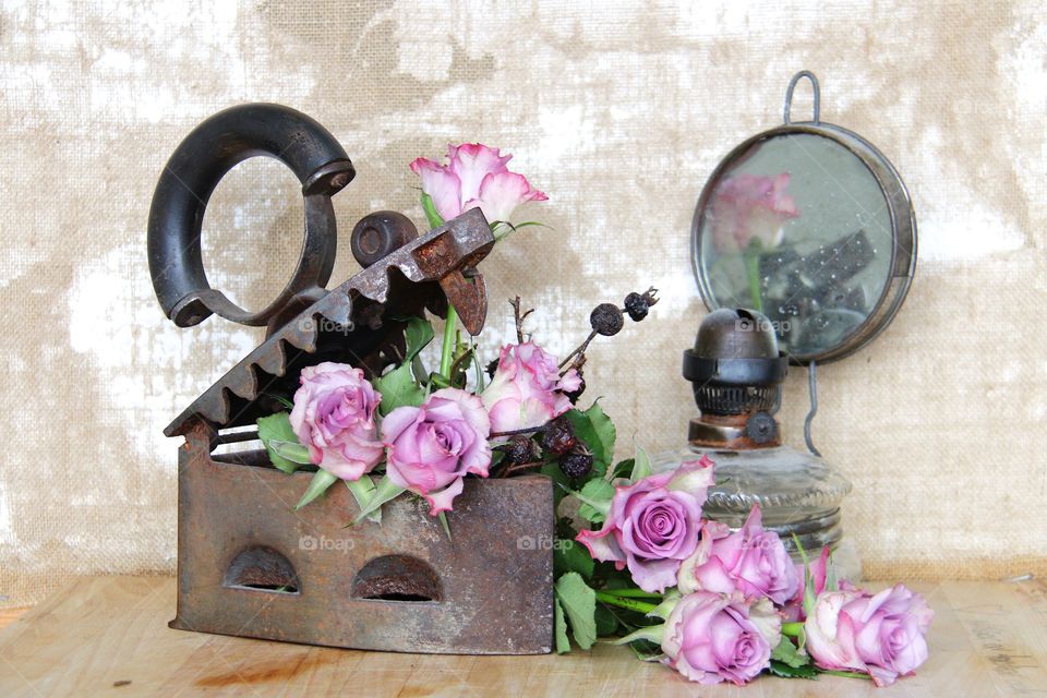 Pink roses in a iron and an old oil lamp