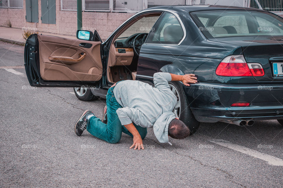 Guy trying to repair his broken car