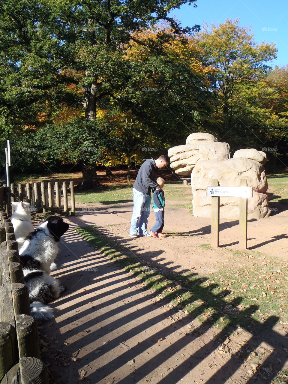 Father and son standing dog near statue