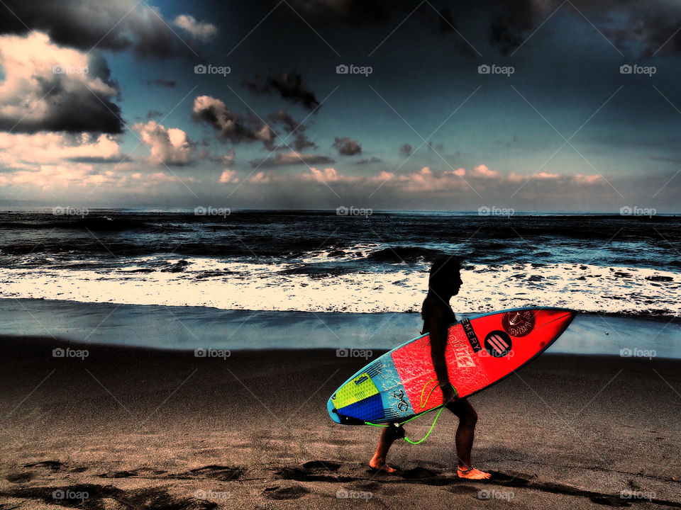 Female surfer walking on beach with surfboard 