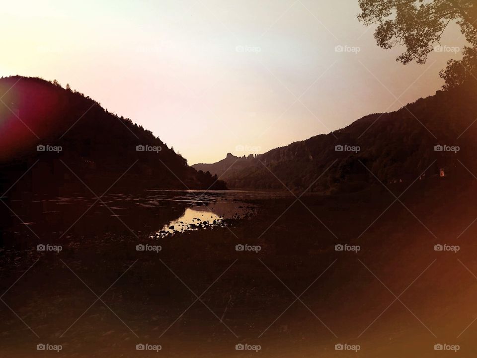 Moody sunset at the river Elbe with reflection of the dusty orange sky