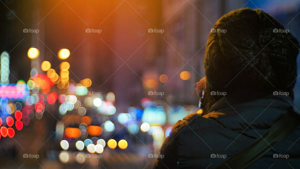 Dream. Staring off into city lights, contemplating thoughts. A person's back and city lights in bokeh in the background