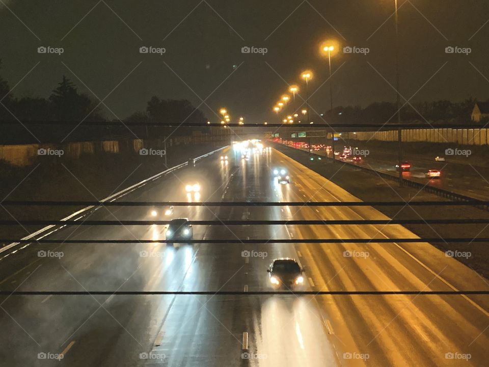 After dark, in the Midwest. A look down onto the Highway, from a city bridge. It’s raining.