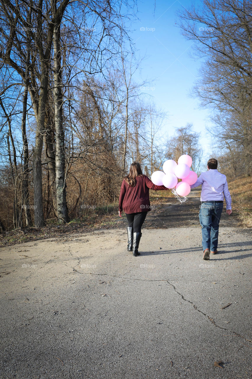 Soon-to-be parents walking with pink balloons outside for gender reveal