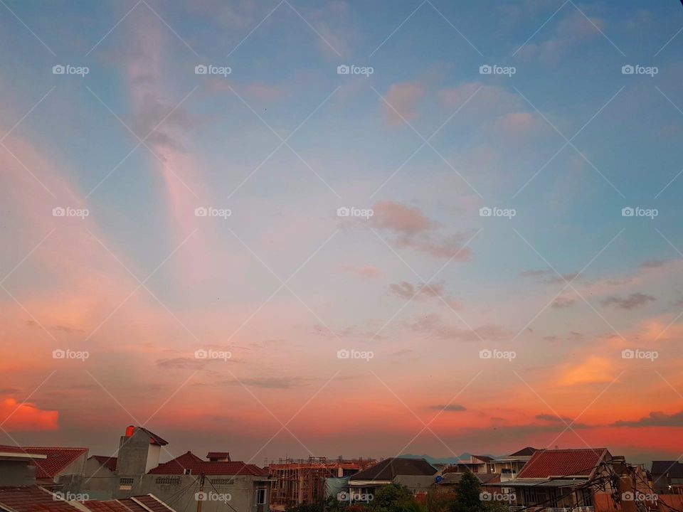 The view in the evening, before sunset, clouds refract red orenge yellow, the sky looks a little blue, its still a little bright, the residential light are still off, beautiful color  view, beutiful clouds and sky,