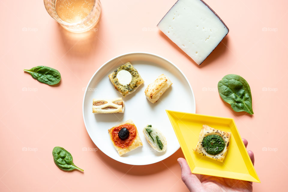 Flat lay of a plate of appetizers and a person’s hand holding an appetizer plate 