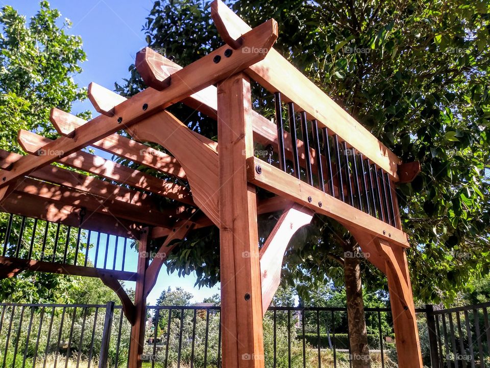 pergola of red stained wood from below and at a diagnol angle