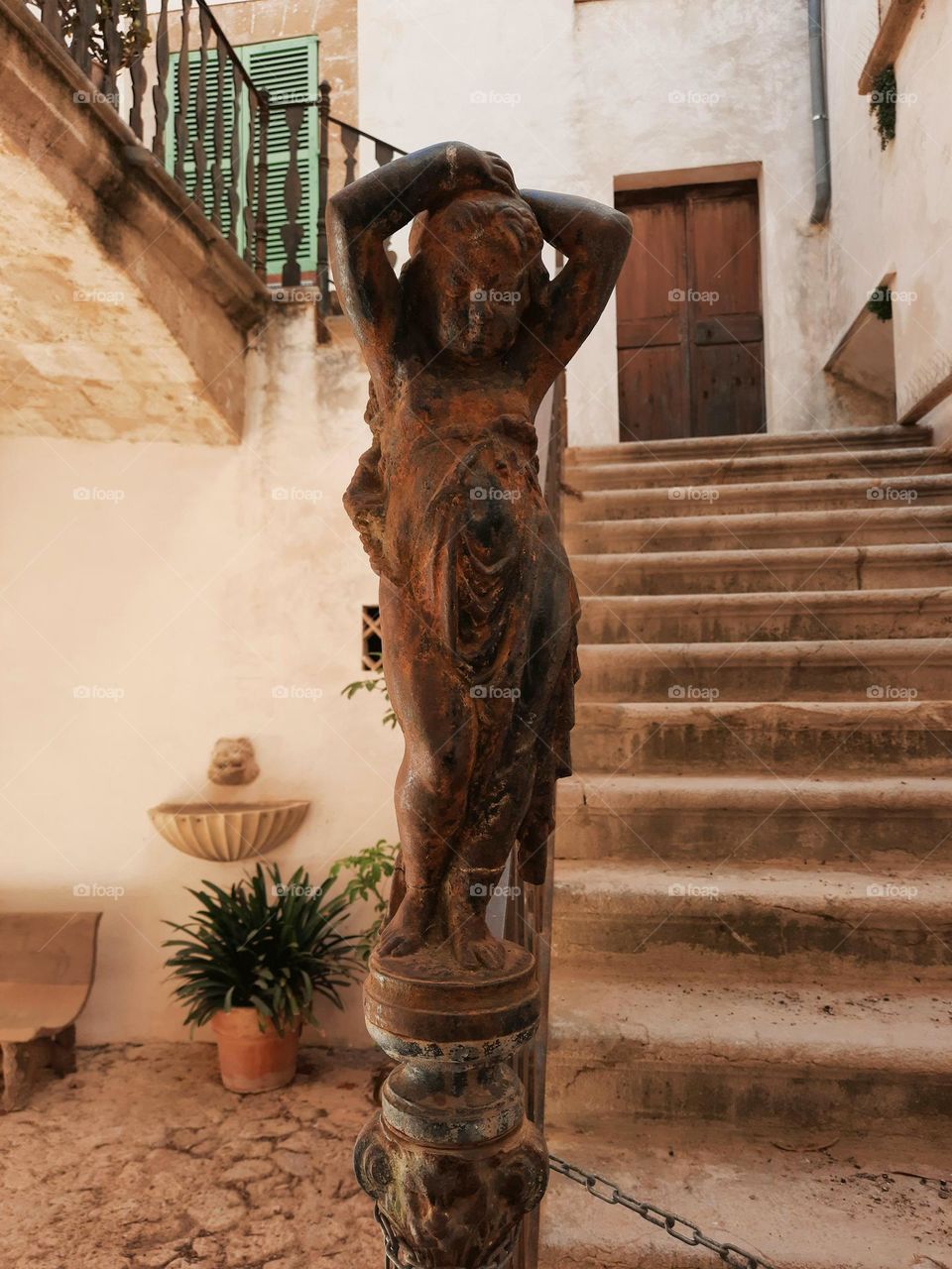 Cast iron figure of a young girl at an ancient staircase. Situated at a courtyard of a Mediterranean traditional manor. Calvia, Majorca, Spain.