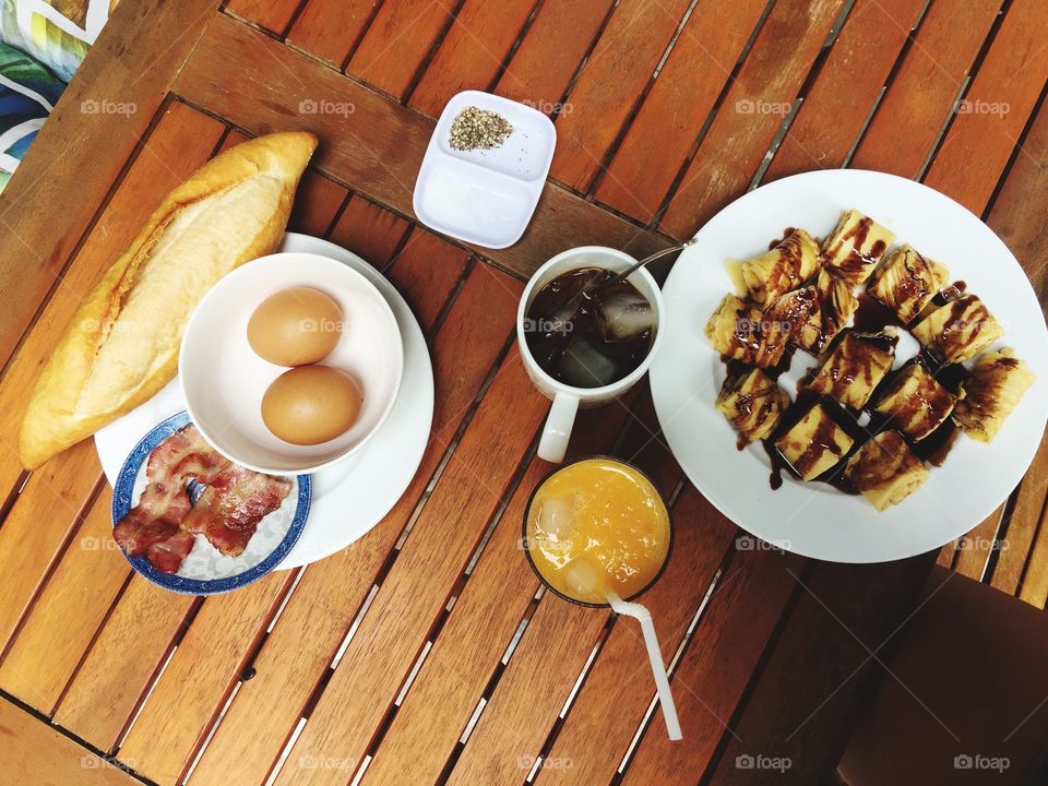 Breakfast table with pancakes eggs bacon sausage coffee orange juice 