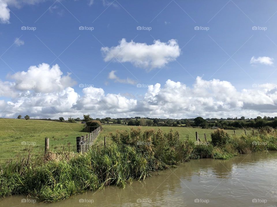 Late morning narrowboat cruise on Oxford canal near Willoughy clear sunny sky lovely late summer weather vacation holiday English country field farm clouds 