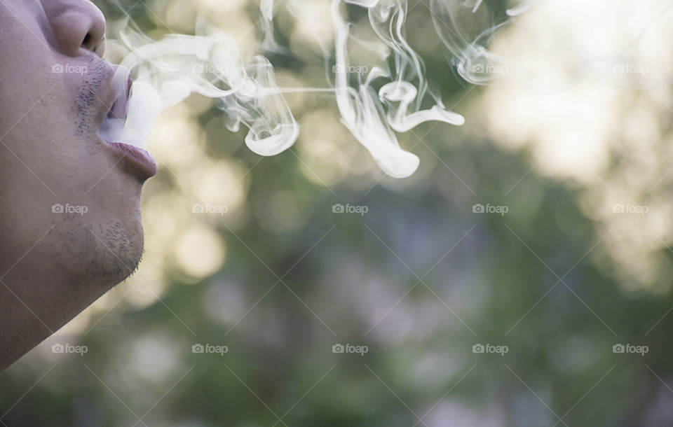 Smoke out of the mouth of a man.